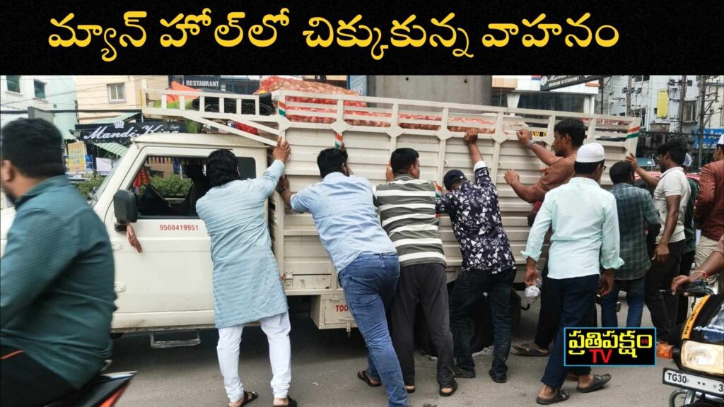 Panjagutta:పంజాగుట్టలో మాన్హోల్లో చిక్కుకున్న వాహనం హైదరాబాద్ పంజాగుట్టలో మాన్హోల్లో చిక్కుకున్న వాహనాన్ని ప్రజలు తోసి బయటకు తీయడం – Hyderabad drainage issue photo by PrathipakshamTV